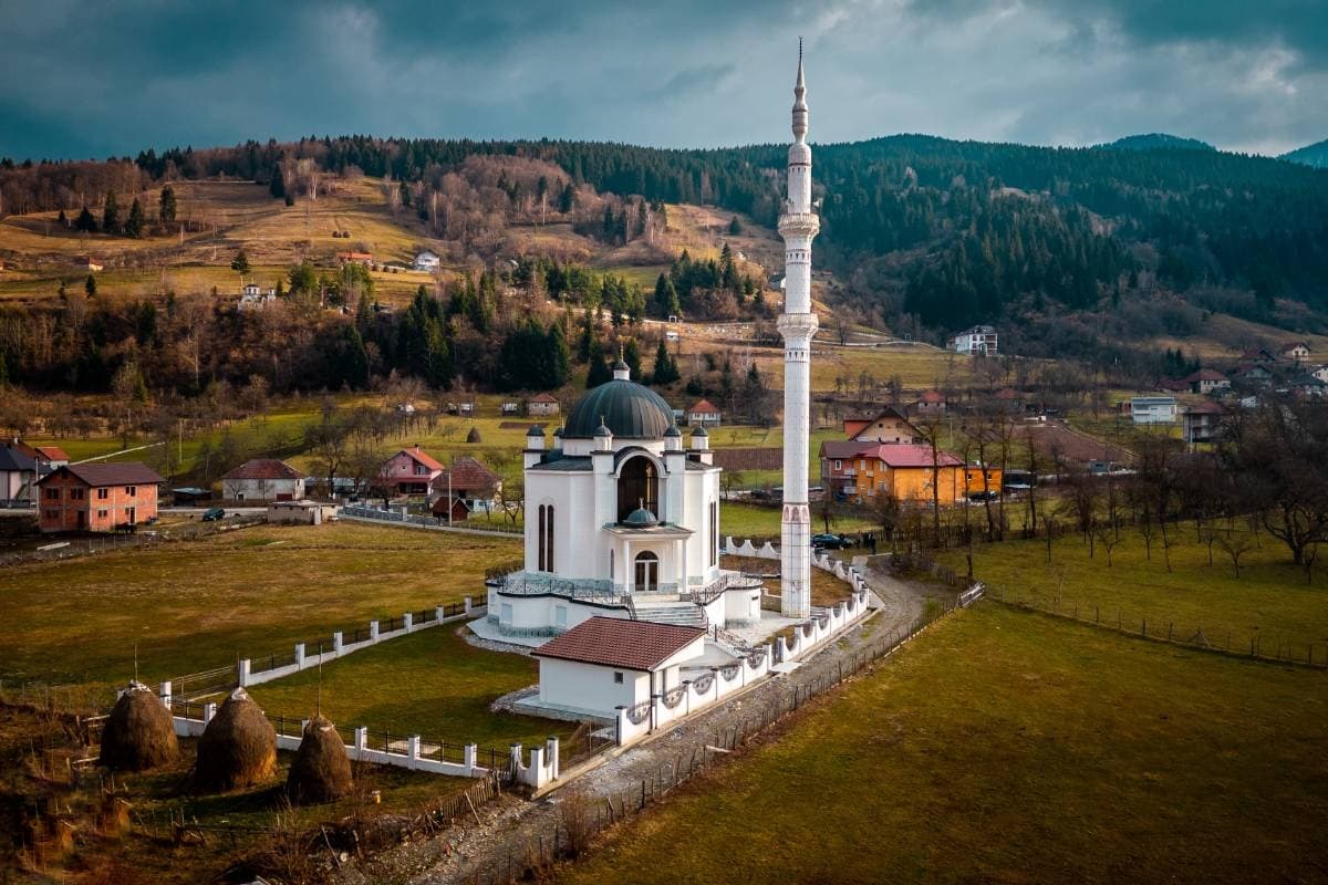 Bijela Šehidska džamija s kupolom i visokom munarom okružena livadama